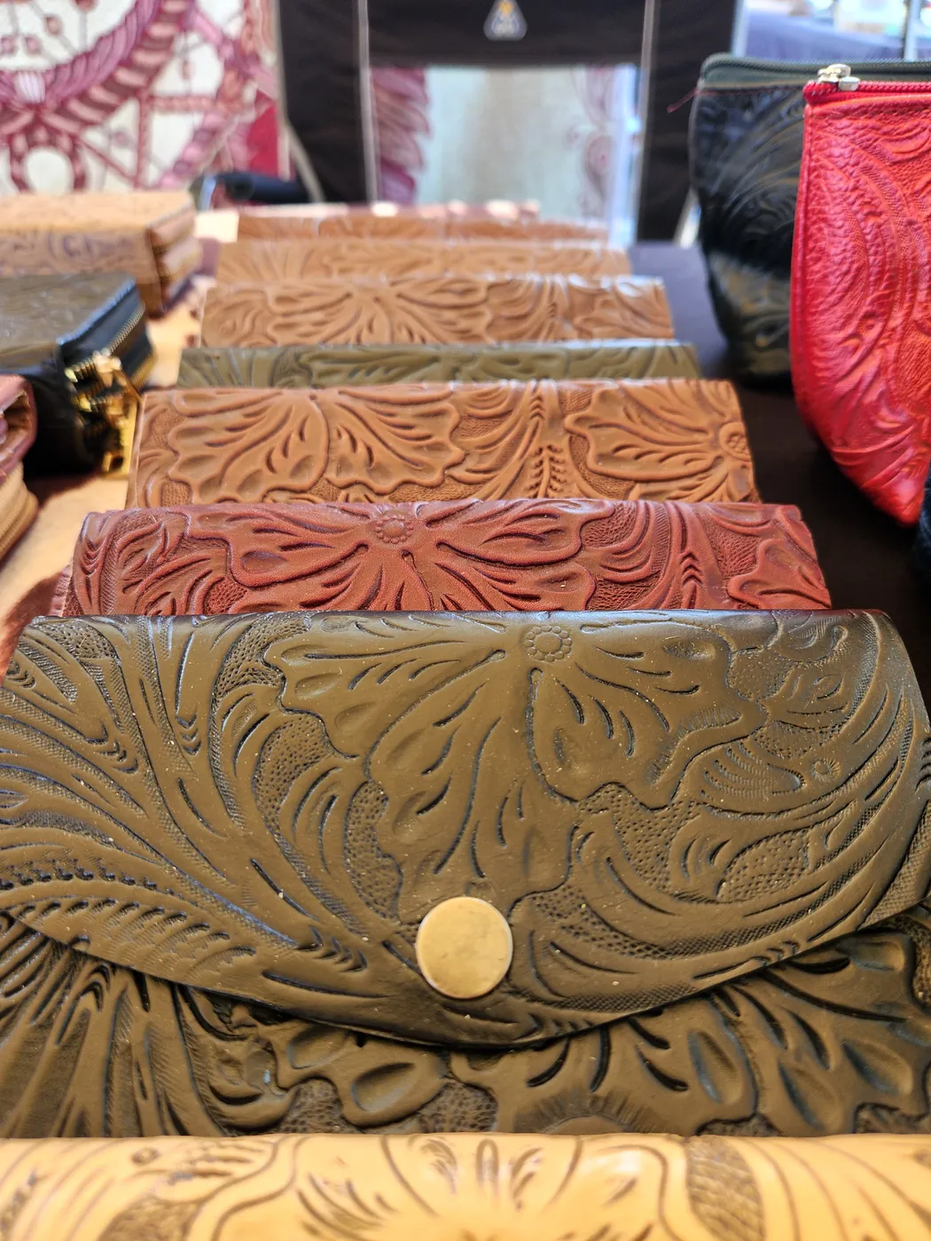 Rows of hand-tooled leather wallets in green, tan and red